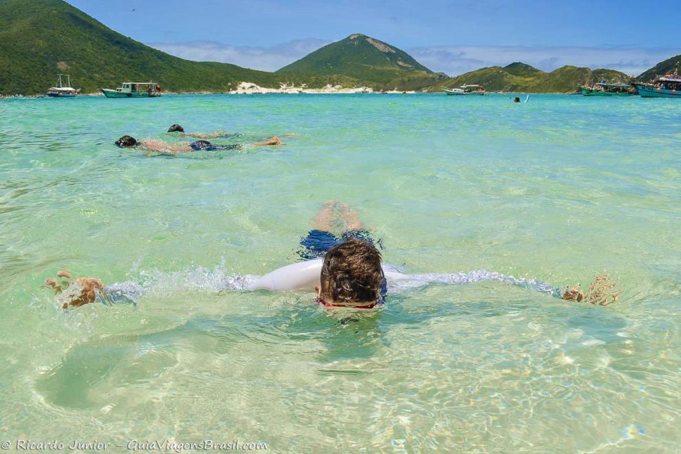 Imagem de crianças mergulhando nas águas claras da Praia do Pontal do Atalaia.